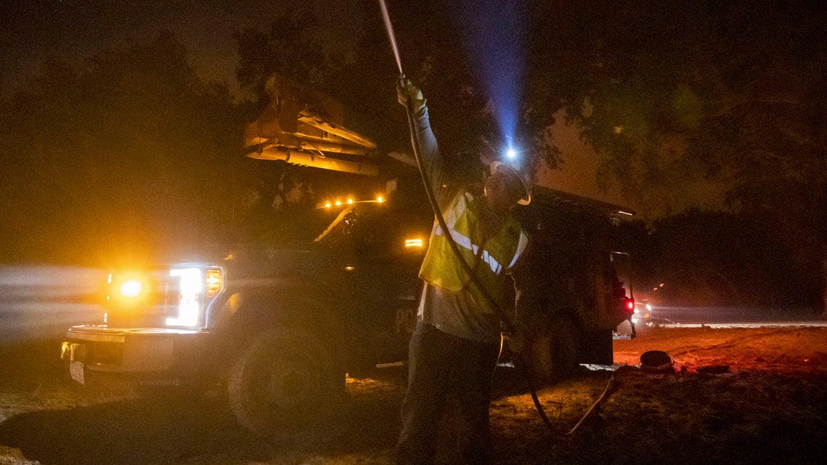 In this Sept. 28, 2020 file photo, a Pacific Gas and Electric employee sprays water on a burning telephone pole at the Zogg Fire near Ono, Calif.