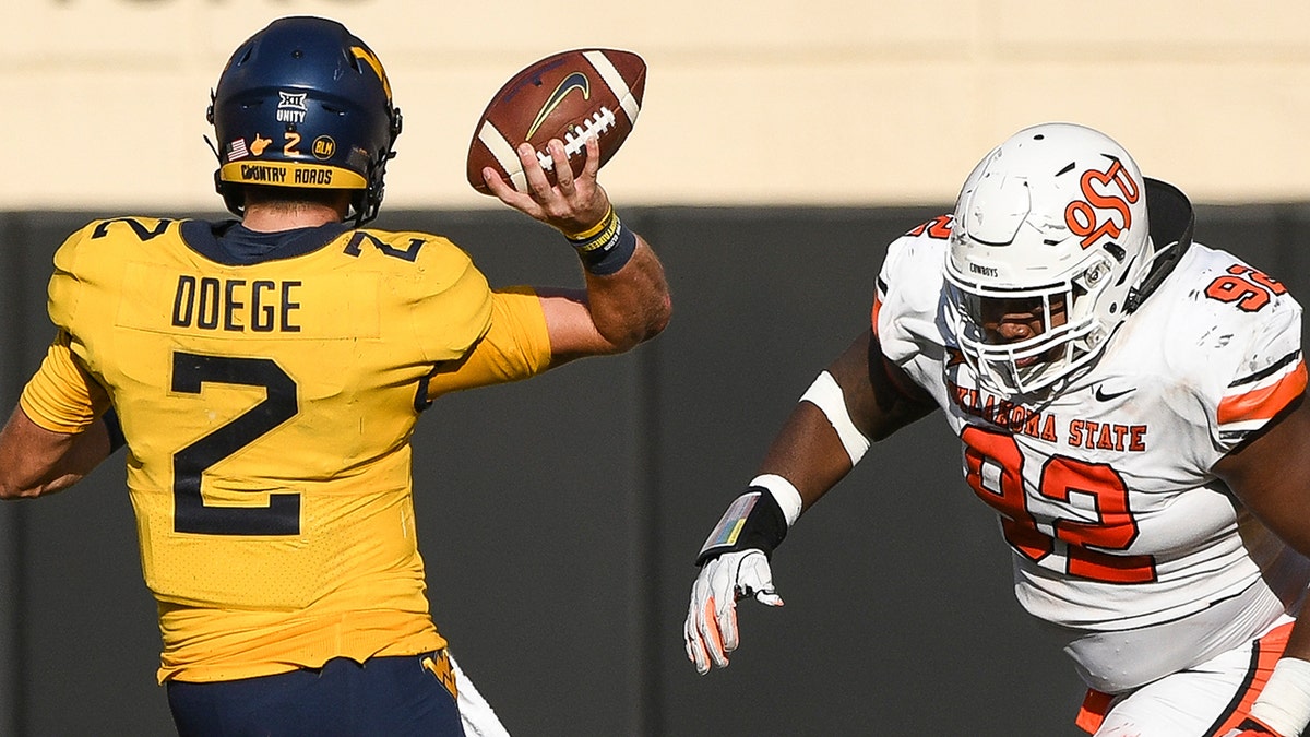 Oklahoma State defensive tackle Cameron Murray (92) runs toward West Virginia quarterback Jarret Doege (2) during the first half of an NCAA college football game Saturday, Sept. 26, 2020, in Stillwater, Okla. (AP Photo/Brody Schmidt)