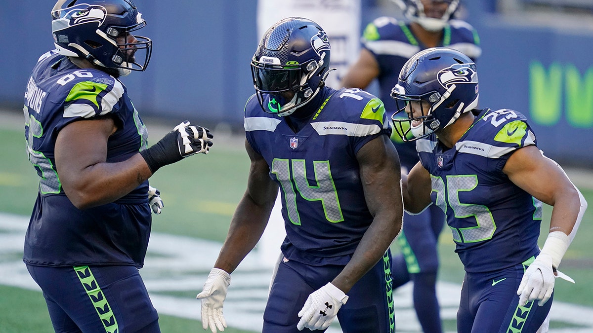 Seattle Seahawks wide receiver DK Metcalf (14) celebrates with Jordan Simmons, left, and Travis Homer, right, after Metcalf scored a touchdown during the second half of an NFL football game, Sunday, Sept. 27, 2020, in Seattle. The Seahawks won 38-31. (AP Photo/Elaine Thompson)