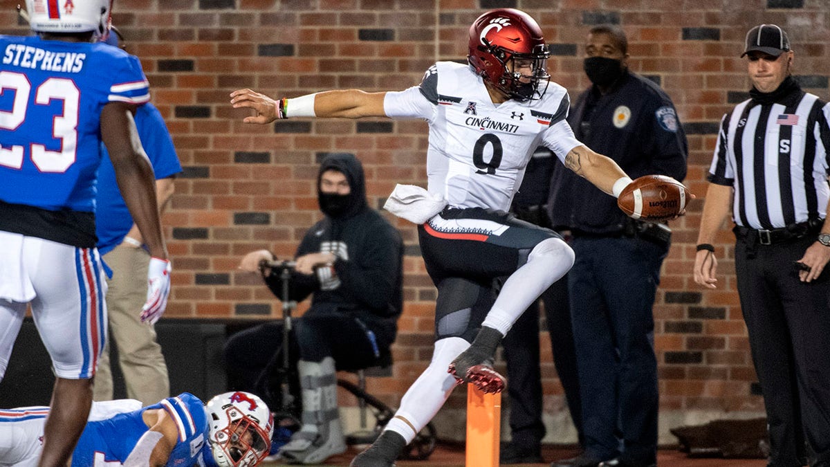 Cincinnati quarterback Desmond Ridder (9) runs for a touchdown past SMU safety Roderick Roberson Jr., bottom left, and defensive back Brandon Stephens (23) during the first half of an NCAA college football game Saturday, Oct. 24, 2020, in Dallas. (AP Photo/Jeffrey McWhorter)