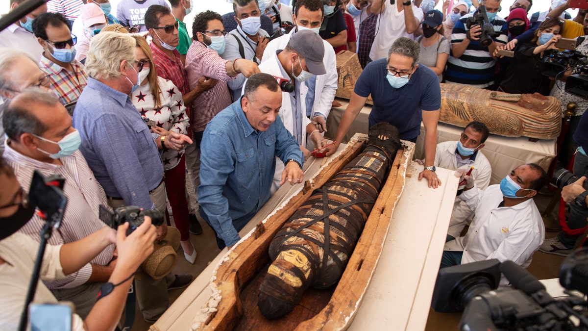 Khalid el-Anany, Egypt's tourism and antiquities minister, right, and Mostafa Waziri, secretary-general of the country's Supreme Council of Antiquities, left, stand over a sarcophagus at the Saqqara archaeological site, 19 miles south of Cairo, Egypt on Saturday, Oct. 3, 2020.