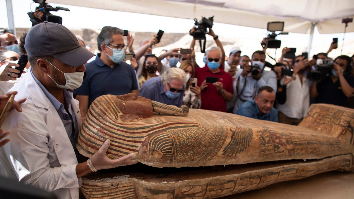 An archaeology worker opens a sarcophagus at the Saqqara archaeological site, 30 kilometers 19 miles south of Cairo, Egypt, on Saturday, Oct. 3, 2020, in the presence of journalists and officials.