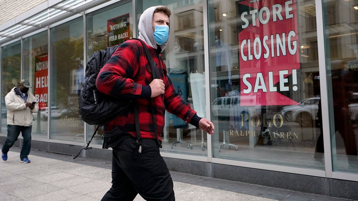 A passer-by walks past a store closing sign, right, in the window of a department store in Boston. Americans may feel whiplashed by a report Thursday, Oct. 29, on the economy's growth this summer, when an explosive rebound followed an epic collapse. The government estimate that the economy grew faster on an annualized basis last quarter than in any such period since record-keeping began in 1947. (AP Photo/Steven Senne)