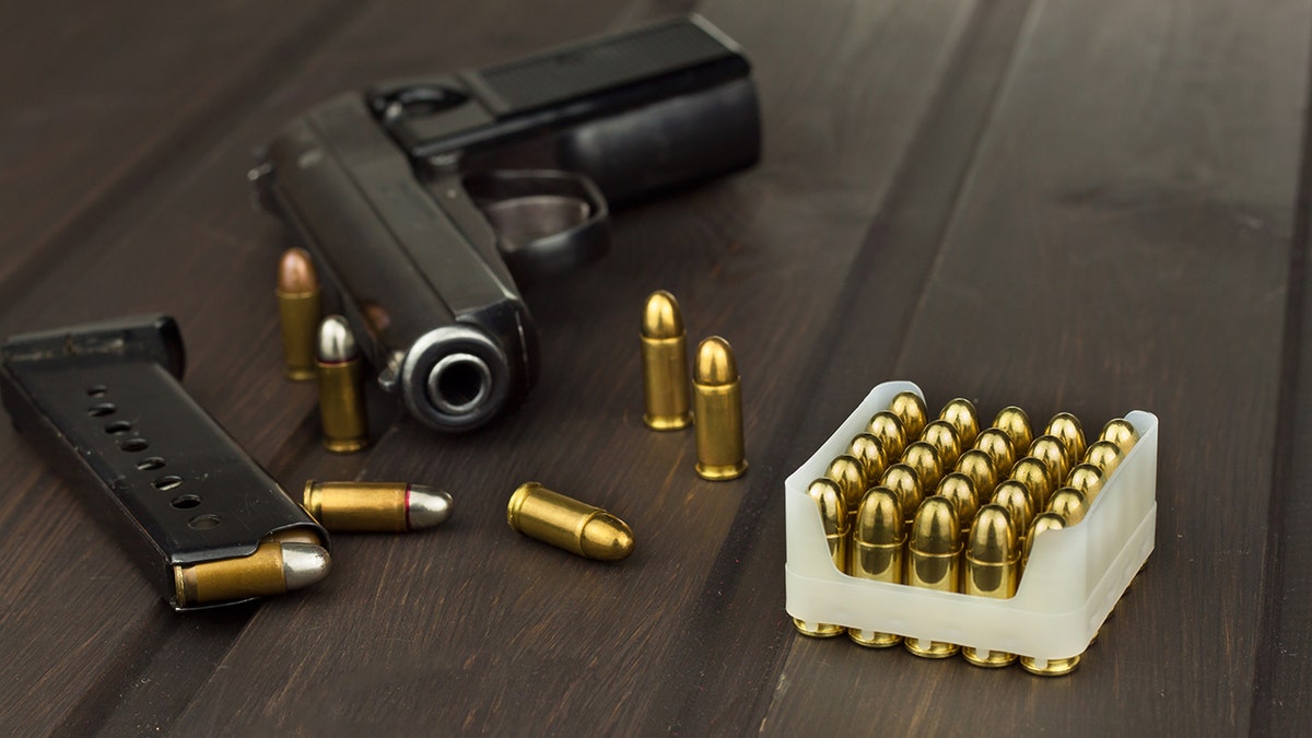 A handgun and bullets on a wooden table