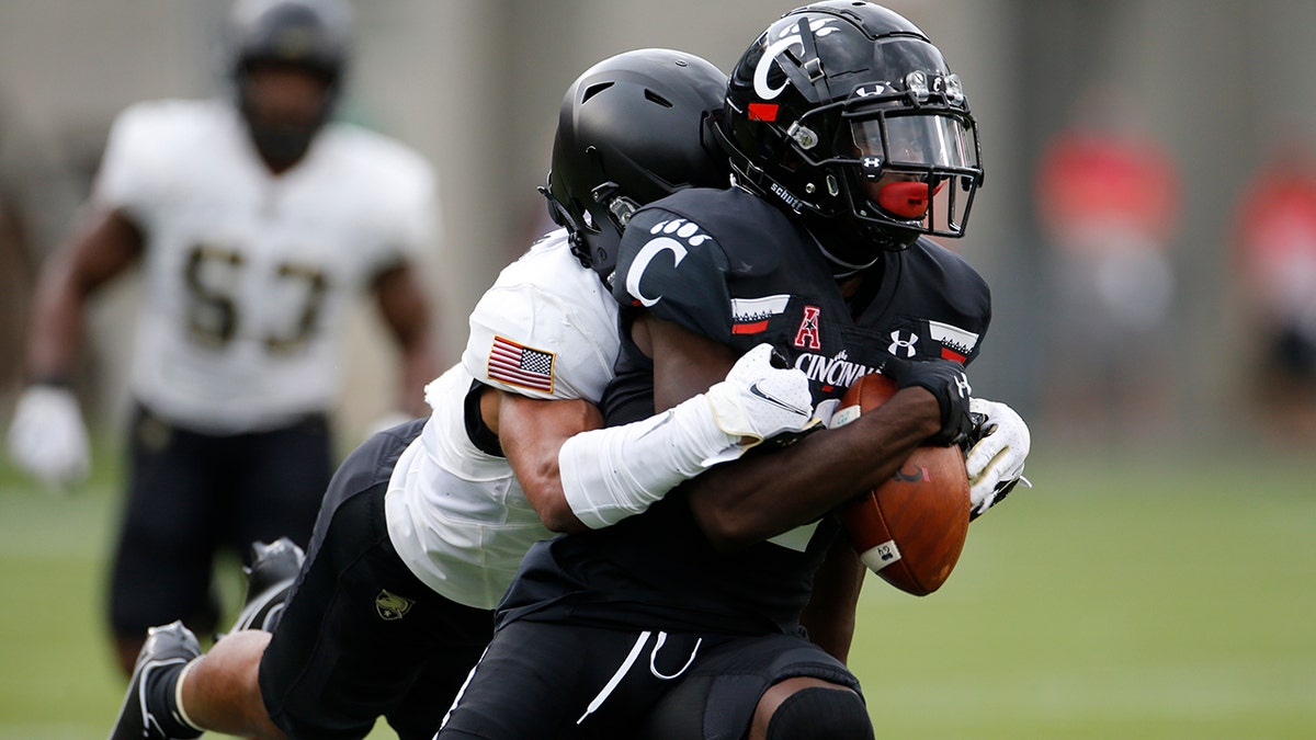 Army defensive back Javhari Bourdeau, left, tackles Cincinnati wide receiver Jayshon Jackson after a catch during the first half of an NCAA college football game Saturday, Sept. 26, 2020, in Cincinnati, Ohio. (AP Photo/Jay LaPrete)