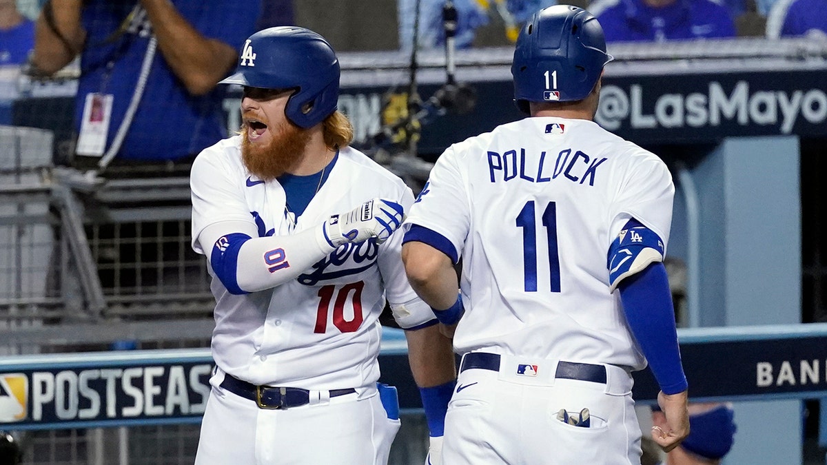 Los Angeles Dodgers' Justin Turner, left, and A.J. Pollock (11) celebrate after Pollock scored on a double by Mookie Betts during the fifth inning in Game 2 of the team's National League wild-card baseball series Thursday, Oct. 1, 2020, in Los Angeles. (AP Photo/Ashley Landis)