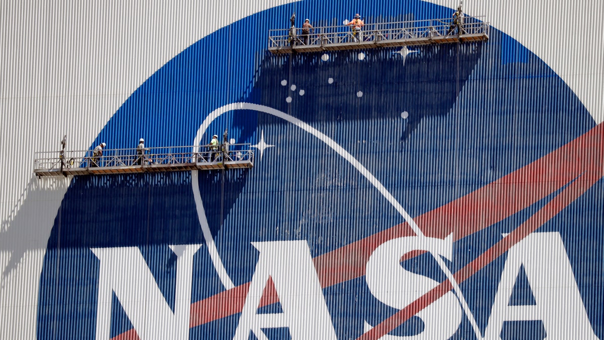 Workers near the top of the 526 ft. Vehicle Assembly Building at the Kennedy Space Center spruce up the NASA logo standing on scaffolds in Cape Canaveral, Fla., Wednesday, May 20, 2020 - file photo.
