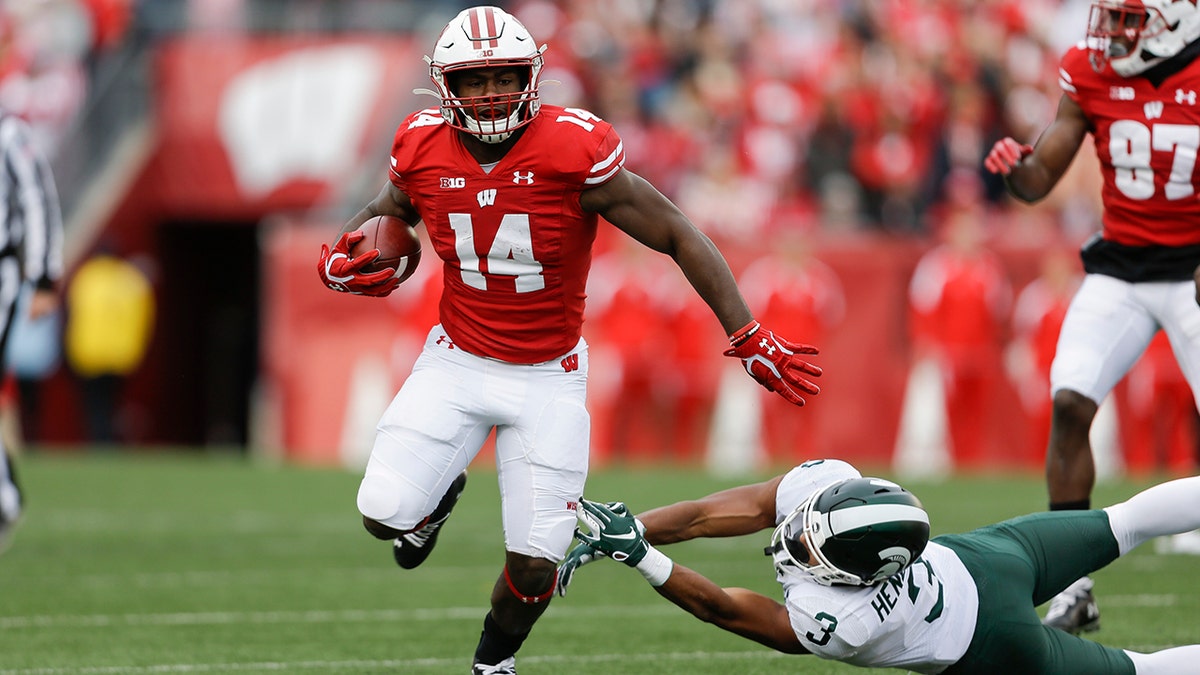 FILE - In this Oct. 12, 2019, file photo, Wisconsin running back Nakia Watson (14) runs past Michigan State safety Xavier Henderson (3) during the first half of an NCAA college football game, in Madison, Wis. (AP Photo/Andy Manis, File)