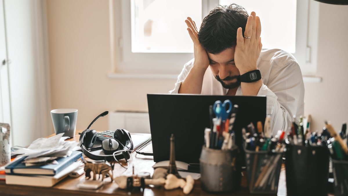 Tired frustrated exhausted businessman working from home online sitting at home office with laptop during quarantine and self isolation period at pandemic. Crisis management. Despair of market falling down.