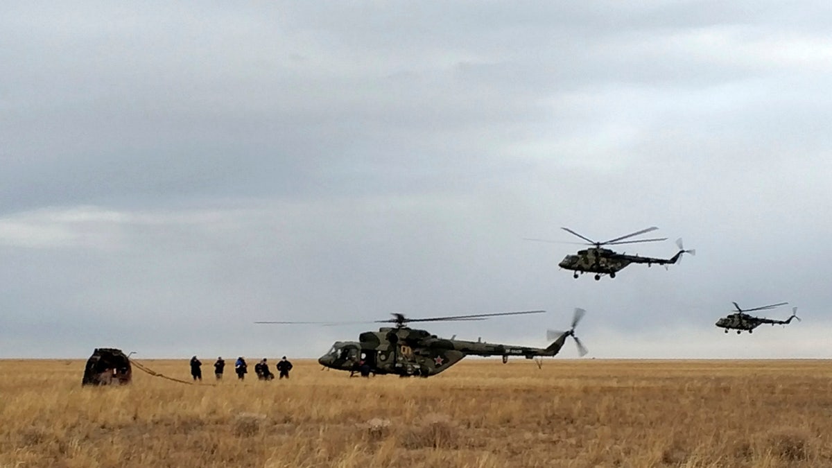 In this photo released by Rosaviatsiya, Russian rescue team helicopters land near a Russian Soyuz MS-16 capsule, left, landed near town of Dzhezkazgan, Kazakhstan, Thursday, Oct. 22, 2020. Rosaviatsiya via AP