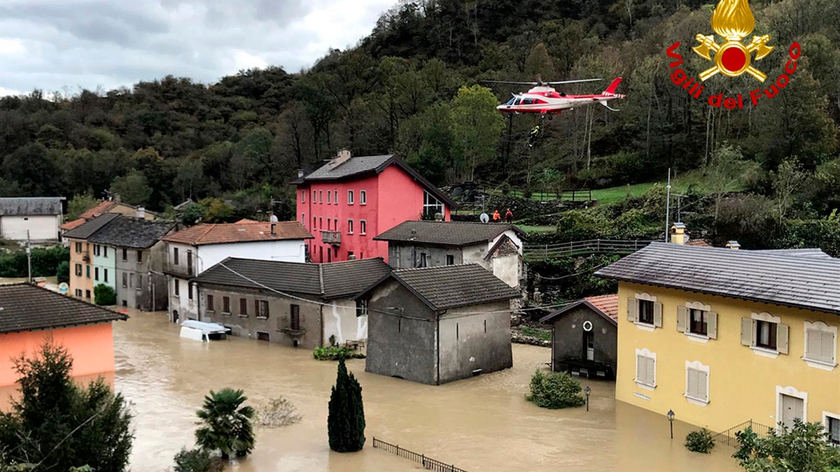In this image made available Sunday, Oct. 4, 2020, a firefighters' helicopter flies over flooding in the town of Ornavasso, in the northern Italian region of Piedmont.