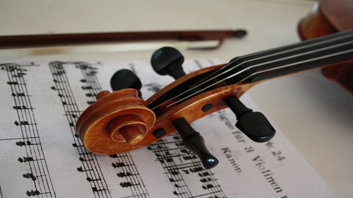 A violin placed over a piece of sheet music. 