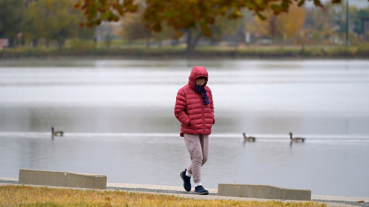 Bundled up against the cold, a man navigates the trail around Sloans Lake after a cold front dropped temperatures Sunday, Oct. 18, 2020, in Denver. (AP Photo/David Zalubowski)