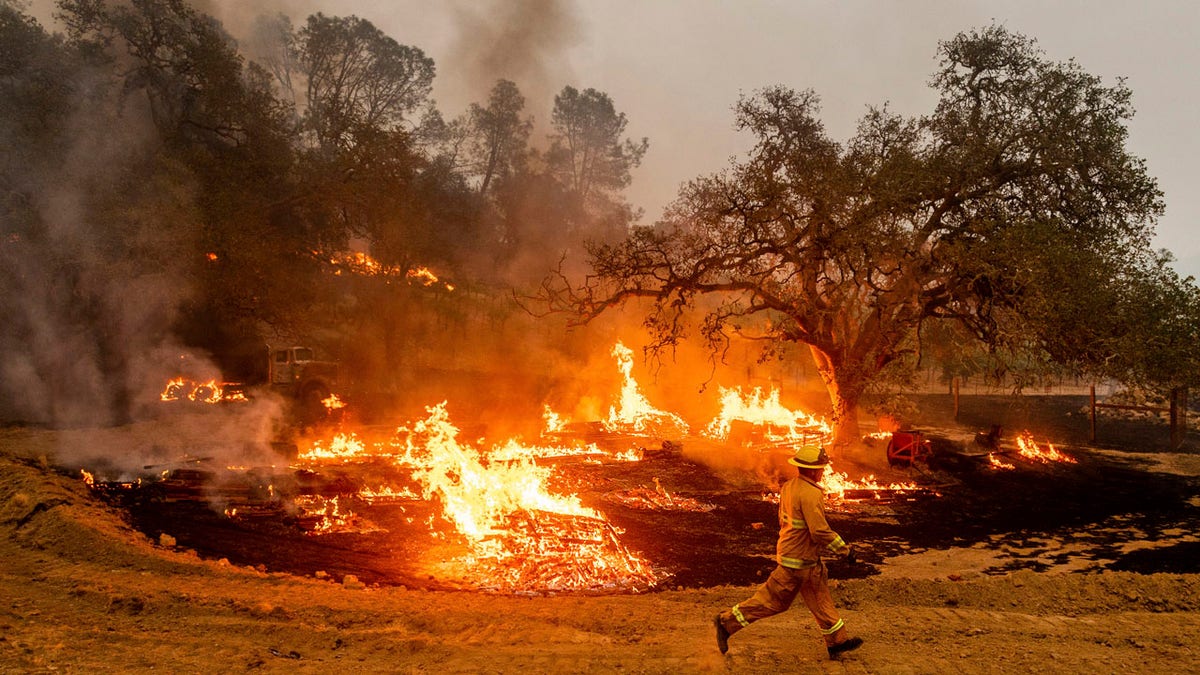 A firefighter runs past flames while battling the Glass Fire in a Calistoga, Calif., vineyard Thursday, Oct. 1, 2020.