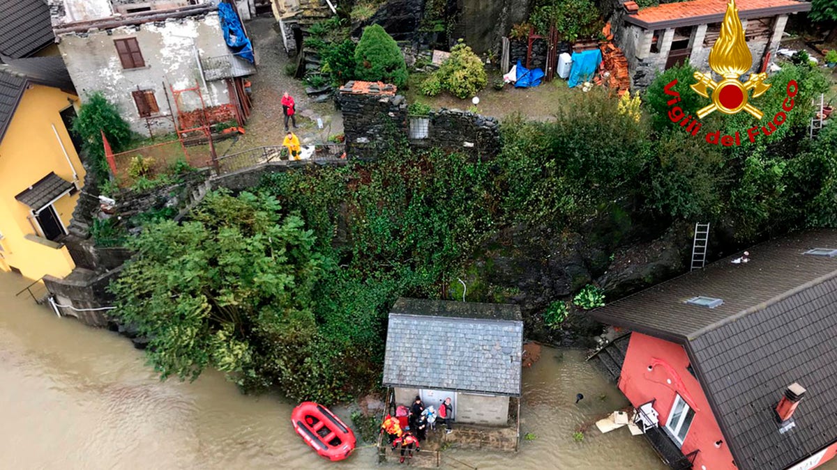 In this image made available Sunday, Oct. 4, 2020, firefighters evacuate people from a house amidst flooding in the town of Ornavasso, in the northern Italian region of Piedmont.
