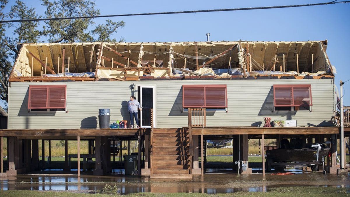 A woman walks out of a house where the roof was torn away during Hurricane Zeta, as people begin the process of cleaning and rebuilding in Chauvin, La., Thursday, Oct. 29, 2020. (Chris Granger/The Times-Picayune/The New Orleans Advocate via AP)