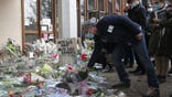 A man lays a flower outside the school where a slain history teacher was working, Saturday, Oct. 17, 2020 in Conflans-Sainte-Honorine, northwest of Paris. French President Emmanuel Macron denounced what he called an "Islamist terrorist attack" against a history teacher decapitated in a Paris suburb Friday, urging the nation to stand united against extremism. The teacher had discussed caricatures of Islam's Prophet Muhammad with his class, authorities said. The suspected attacker was shot to death by police after Friday's beheading. (AP Photo/Michel Euler)
