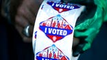 FILE - In this Saturday, Oct. 17, 2020, file photo a poll worker displays "I Voted" stickers during the first day of early voting in Las Vegas. Democrats have kept Nevada in their column in every presidential election since 2004. But political strategists and organizers on the ground warn Nevada is still a swing state. (Steve Marcus/Las Vegas Sun via AP, File)
