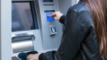 woman hand showing dollar banknotes in front of the atm