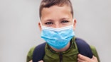 Child wear facemask during coronavirus and flu outbreak. The boy wear a mask before going to school preventing outbreak Infectious disease and dust in the air.