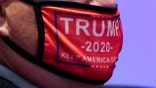 CHARLOTTE, NORTH CAROLINA - AUGUST 24: A delegate wearing a 'Trump 2020' face mask arrives for the start of the first day of the Republican National Convention at the Charlotte Convention Center on August 24, 2020 in Charlotte, North Carolina. (Photo by Chris Carlson - Pool/Getty Images)