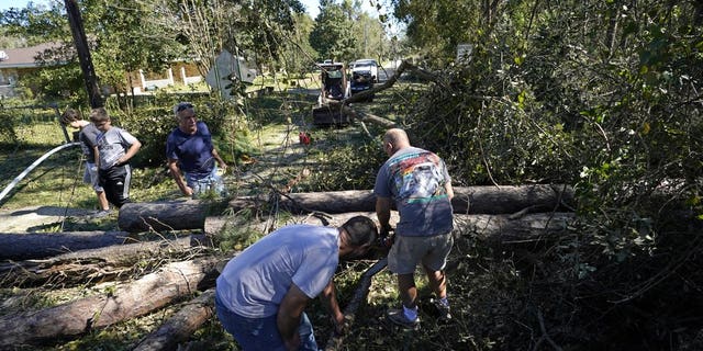 Residents use chain saws to clear fallen trees in the aftermath of Hurricane Zeta in Waveland, Miss., Thursday, Oct. 29, 2020. (AP Photo/Gerald Herbert)
