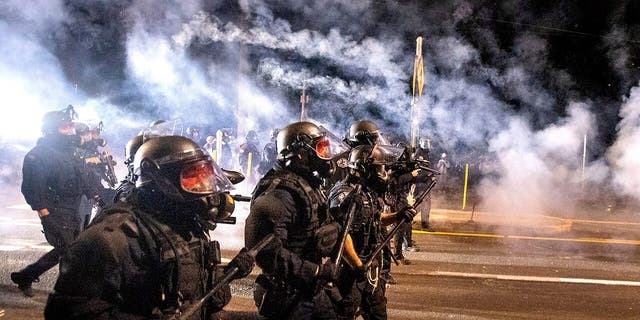 Police use chemical irritants and crowd control munitions to disperse protesters during the 100th consecutive day of demonstrations in Portland, Ore., on Saturday, Sept. 5, 2020. According to an officer, police responded with stronger tactics after a molotov cocktail was thrown.(AP Photo/Noah Berger)