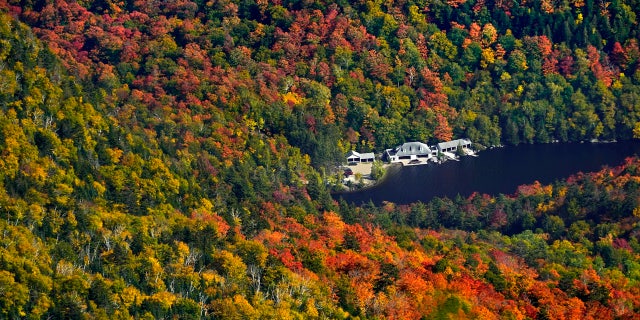 Waterfront buildings at The Ausable Club are surrounded by a forest of changing colors as viewed from Gothics Mountain, Saturday, Sept. 26, 2020, in New York's Adirondack Park.