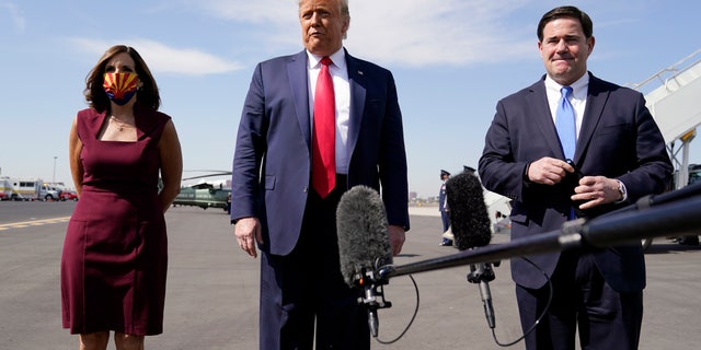 President Donald Trump talks to reporters at Phoenix Sky Harbor International Airport, Monday, Oct. 19, 2020, in Phoenix, with Sen. Martha McSally, R-Ariz., and Arizona Gov. Doug Ducey. (AP Photo/Alex Brandon)