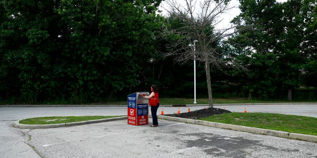 FILE - In this July 1, 2020, file photo, a New Jersey woman drops off her ballot for the New Jersey primary election at a vote-by-mail drop box in a parking lot at Camden County College in Cherry Hill, N.J. Amid the global pandemic, more people than ever are expected to bypass their polling place and cast absentee ballots for the first time. Voters marking ballots from home could lead to an increase in the kinds of mistakes that typically would be caught by a scanner or election worker at the polls. (AP Photo/Matt Slocum, File)