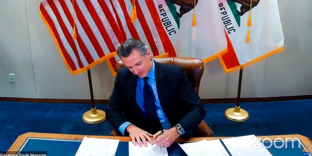 This image made from video from the Office of the Governor shows California Gov.  Gavin Newsom signing into law a bill that establishes a task force to come up with recommendations on how to give reparations to Black Americans on Sept.  30, 2020, in Sacramento, Calif.