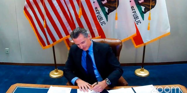 This image made from video from the Office of the Governor shows California Gov.  Gavin Newsom signing into law a bill that establishes a task force to come up with recommendations on how to give reparations to Black Americans on Sept.  30, 2020, in Sacramento, Calif.