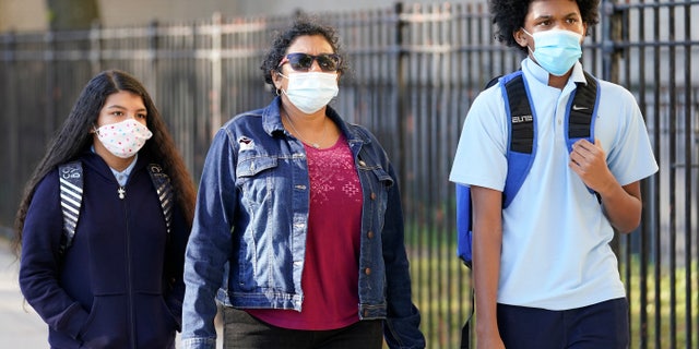 A mother accompanies her children on Thursday, October 1, 2020, in New York, for the first day of personal tuition at Erasmus High School in Brooklyn's Flatbush neighborhood. The city's plans to send children back to the classrooms are based on an ambitious plan to run random virus tests on students and staff throughout the school year. (AP Photo / Mark Lennihan)