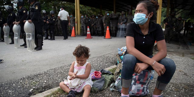 An Honduran migrant and her daughter sit at a roadblock set by security forces in Poptun, Guatemala, Friday, Oct. 2, 2020. (Associated Press)