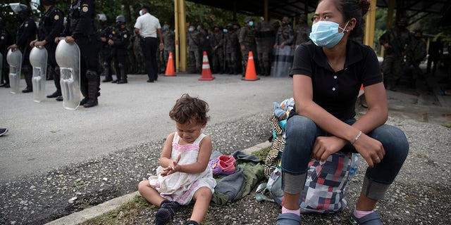 An Honduran migrant and her daughter sit at a roadblock set by security forces in Poptun, Guatemala, Friday, Oct. 2, 2020. (Associated Press)