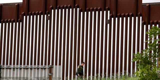 In this March 18 photo, a Border Patrol agent walks along a border wall separating Tijuana, Mexico, from San Diego, in San Diego. (AP Photo/Gregory Bull, File)