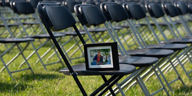 A photograph of Leo Villanueva who lost his life due the COVID-19, sits in one of the thousands of empty chairs, who represent a fraction of the more than 200,000 lives lost due the COVID-19 are seen during the National COVID-19 Remembrance, at The Ellipse outside of the White House, Sunday, Oct. 4, 2020, in Washington. (AP Photo/Jose Luis Magana)