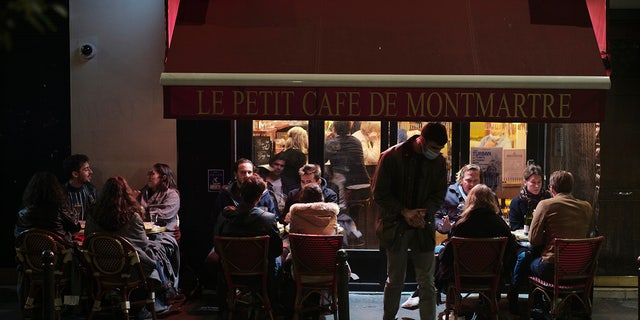 In this Sept. 26, 2020 file photo, people enjoy a drink in a cafe terrace in Paris. French authorities have placed the Paris region on maximum virus alert on Monday, banning festive gatherings and requiring all bars to close but allowing restaurants to remain open, as numbers of infections are rapidly increasing. (AP Photo/Lewis Joly, File)