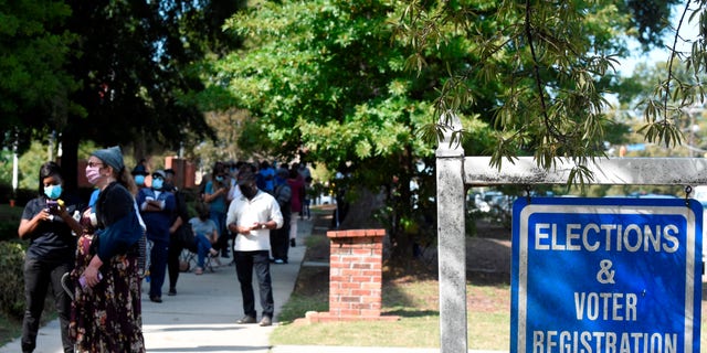 Voters wait in line outside the Richland County election office on the first day of in-person absentee voting in South Carolina on Monday, Oct. 5, 2020, in Columbia, S.C. A number of counties have polling places where people can vote almost like they would in person on Election Day, instead of having to mail in their absentee ballot. (AP Photo/Meg Kinnard)