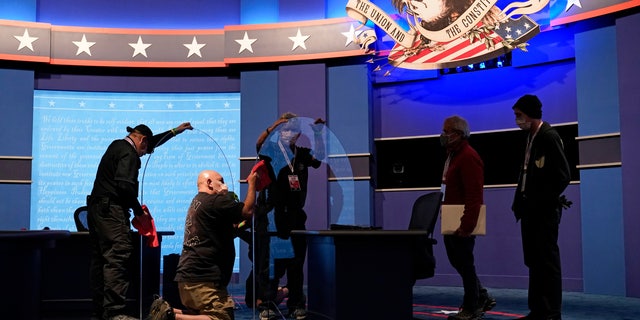 Workers clean protective plastic panels onstage between tables for Vice President Mike Pence and Democratic vice presidential candidate, Sen. Kamala Harris, D-Calif., as preparations take place for the vice presidential debate in Kingsbury Hall at the University of Utah, Tuesday, Oct. 6, 2020, in Salt Lake City. (AP Photo/Patrick Semansky)