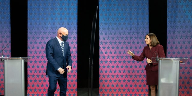 Democratic challenger Mark Kelly, left, arrives to debate U.S. Sen. Martha McSally, R-Ariz., right, at the Walter Cronkite School of Journalism in Phoenix, Ariz., Tuesday, Oct. 6, 2020. (Rob Schumacher/The Arizona Republic via AP, Pool)