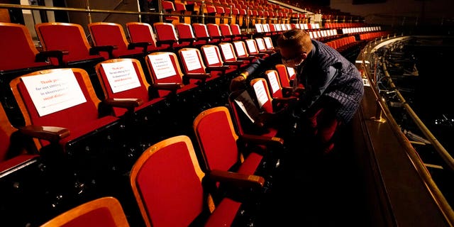 A member of the production staff puts labels on seats in an effort to keep seats socially distanced ahead of the vice presidential debate (AP Photo/Julio Cortez)