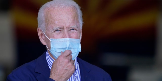 With the Arizona state flag in the background, Democratic presidential candidate former Vice President Joe Biden speaks to members of the media before leaving Phoenix Sky Harbor International Airport, in Phoenix, Thursday, Oct. 8, 2020. (AP Photo/Carolyn Kaster)