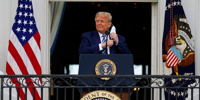 President Donald Trump removes his face mask to speak from the Blue Room Balcony of the White House to a crowd of supporters, Oct. 10, in Washington. (AP Photo/Alex Brandon)
