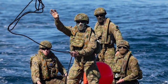 In this Sept. 25, 2020, photo provided by the Royal Australian Navy, members of the Australian Clearance Diving Team One return to Lord Howe Island, Australia, from Elizabeth Reef on a Zodiac inflatable boat following a successful search for unexploded ordnance. The 45-kilogram (100-pound) bomb was found by a fisherman on Elizabeth Reef near Lord Howe Island, about 550 kilometers (340 miles) off New South Wales state. (ABIS Sittichai Sakonpoonpol/Royal Australian Navy via AP)