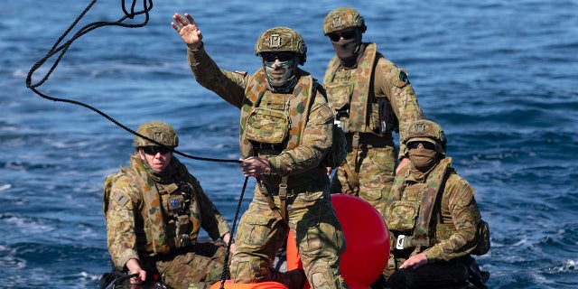 In this Sept. 25, 2020, photo provided by the Royal Australian Navy, members of the Australian Clearance Diving Team One return to Lord Howe Island, Australia, from Elizabeth Reef on a Zodiac inflatable boat following a successful search for unexploded ordnance. The 45-kilogram (100-pound) bomb was found by a fisherman on Elizabeth Reef near Lord Howe Island, about 550 kilometers (340 miles) off New South Wales state. (ABIS Sittichai Sakonpoonpol/Royal Australian Navy via AP)