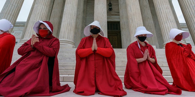 Activists opposing the confirmation of President Donald Trump's Supreme Court nominee, Justice Amy Coney Barrett, are dressed as characters from "The Handmaid's Tale" in the Supreme Court on Capitol Hill in Washington on Sunday, Oct. 11, 2020. Barrett's confirmation hearing begins Monday before the Republican-led Senate Judiciary Committee. (AP Photo/J. Scott Applewhite)