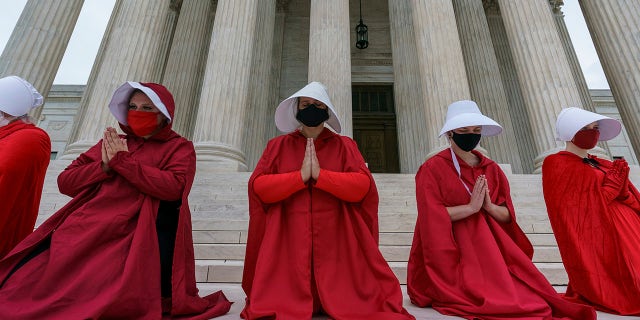 Activists opposed to the confirmation of President Donald Trump's Supreme Court nominee, Judge Amy Coney Barrett, are dressed as characters from "The Handmaid's Tale," at the Supreme Court on Capitol Hill in Washington, Sunday, Oct. 11, 2020. Barrett's confirmation hearing begins Monday before the Republican-led Senate Judiciary Committee.