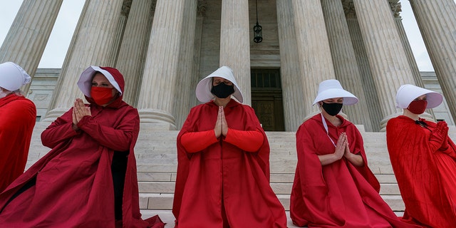 Activists opposed to the confirmation of President Donald Trump's Supreme Court nominee, Judge Amy Coney Barrett, are dressed as characters from "The Handmaid's Tale," at the Supreme Court on Capitol Hill in Washington, Sunday, Oct. 11, 2020. (AP Photo/J. Scott Applewhite)