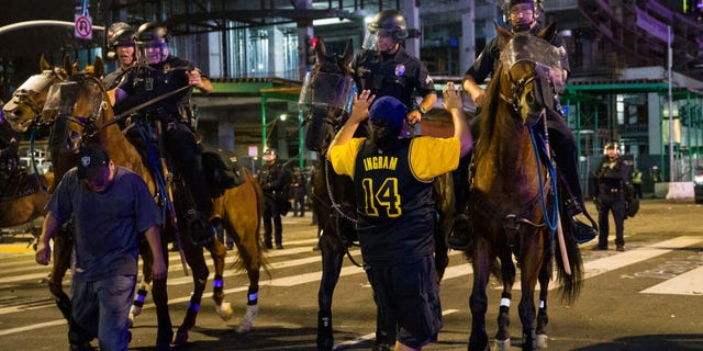 Police on horseback move people back as rowdy fans celebrate, Sunday, Oct. 11, 2020, in Los Angeles, after the Los Angeles Lakers defeated the Miami Heat in Game 6 of basketball's NBA Finals to win the championship. (AP Photo/Jintak Han)